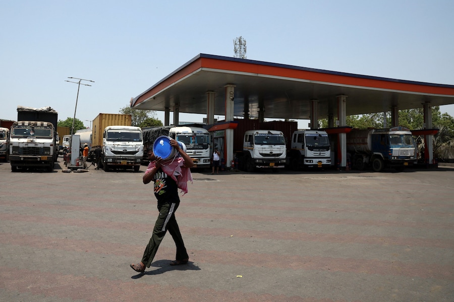 Un addetto al rifornimento che trasporta un contenitore di petrolio passa accanto a dei camion mentre questi fanno rifornimento in una stazione di servizio a Gandhidham, nel Gujarat (India), il 23 maggio 2026. REUTERS/Amit Dave (REUTERS)