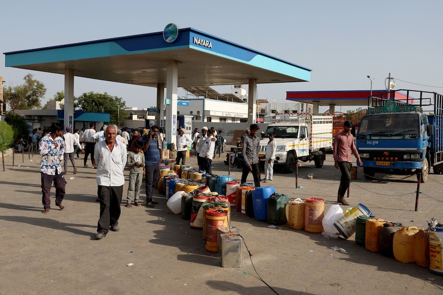 Gli abitanti del villaggio sono in piedi accanto a dei contenitori di plastica sistemati presso una stazione di servizio per rifornire di carburante le loro pompe dell'acqua, mentre l'India deve affrontare l'aumento dei prezzi del petrolio a seguito della chiusura dello Stretto di Hormuz nel contesto del conflitto tra Stati Uniti, Israele e Iran, a Halvad, nel Gujarat (India), il 22 maggio 2026. REUTERS/Amit Dave (REUTERS)