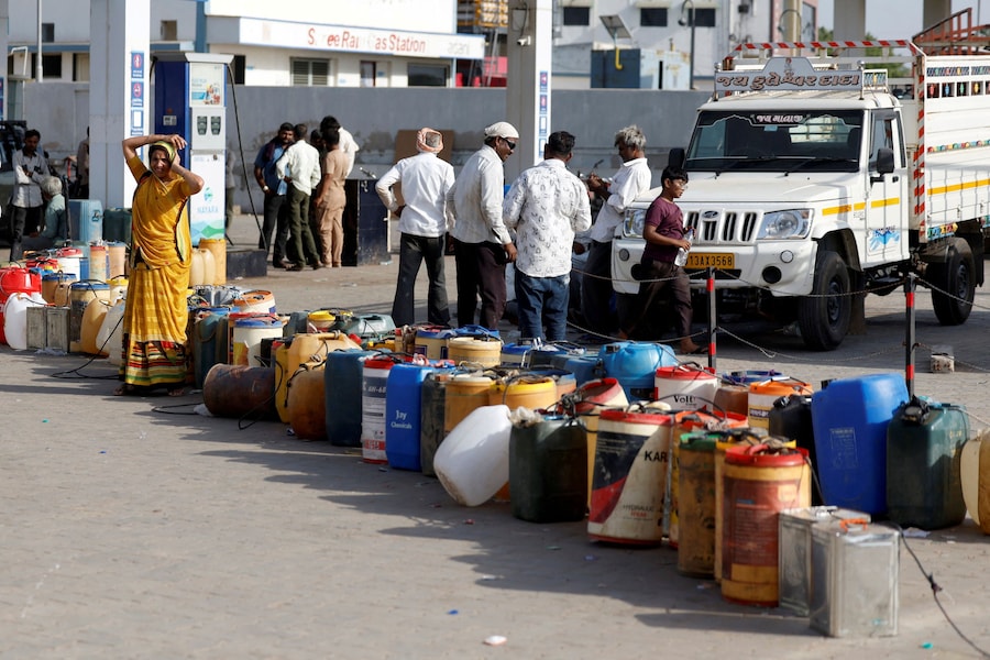 Una donna è in piedi accanto a dei contenitori di plastica collocati presso una stazione di servizio per rifornire di carburante le pompe idriche degli abitanti del villaggio, mentre l'India deve affrontare l'aumento dei prezzi del petrolio a seguito della chiusura dello Stretto di Ormuz nel contesto del conflitto tra Stati Uniti, Israele e Iran, a Halvad, nel Gujarat (India), il 22 maggio 2026. REUTERS/Amit Dave (REUTERS)