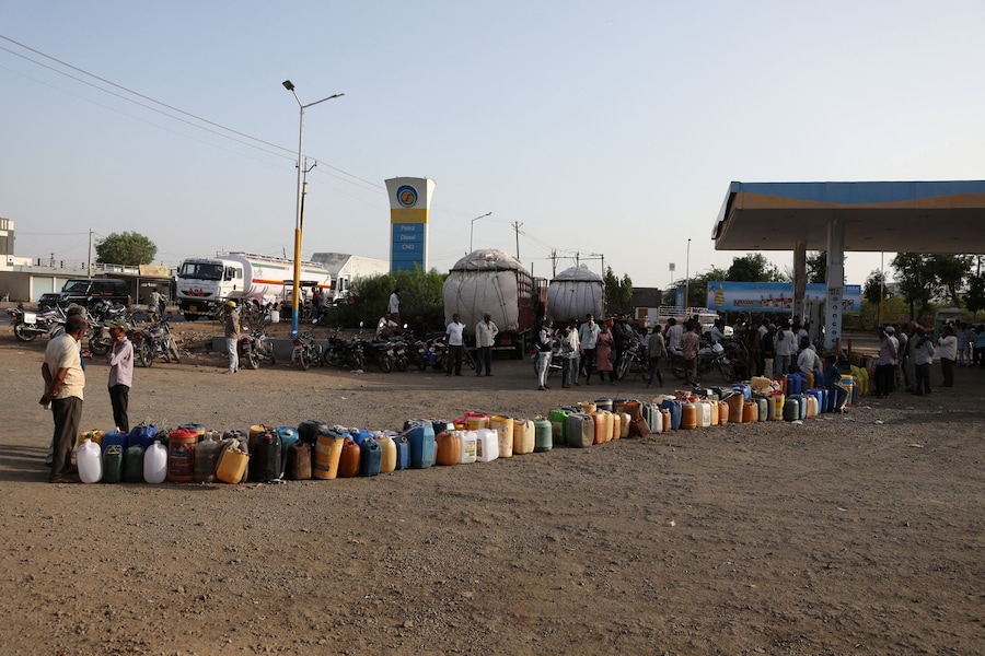 Gli abitanti del villaggio sono in piedi accanto a dei contenitori di plastica sistemati presso una stazione di servizio per rifornire di carburante le loro pompe dell'acqua, mentre l'India deve affrontare l'aumento dei prezzi del petrolio a seguito della chiusura dello Stretto di Hormuz nel contesto del conflitto tra Stati Uniti, Israele e Iran, a Halvad, nel Gujarat (India), il 22 maggio 2026. REUTERS/Amit Dave (REUTERS)