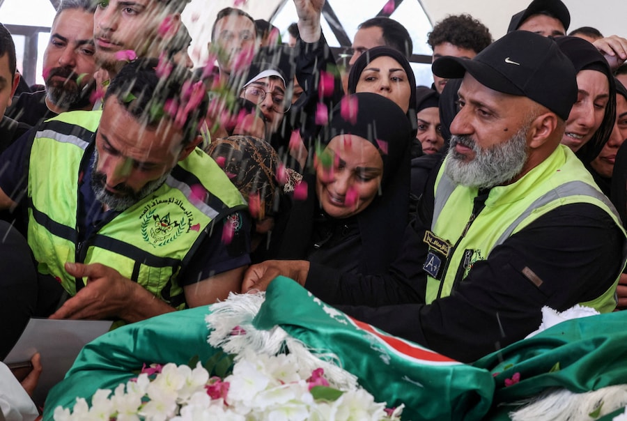 Un partecipante al funerale lancia petali di fiori durante la cerimonia funebre in memoria dei medici uccisi in un attacco israeliano contro la città meridionale di Deir Qanoun En-Nahr, a Tiro, in Libano. (REUTERS/Aziz Taher)