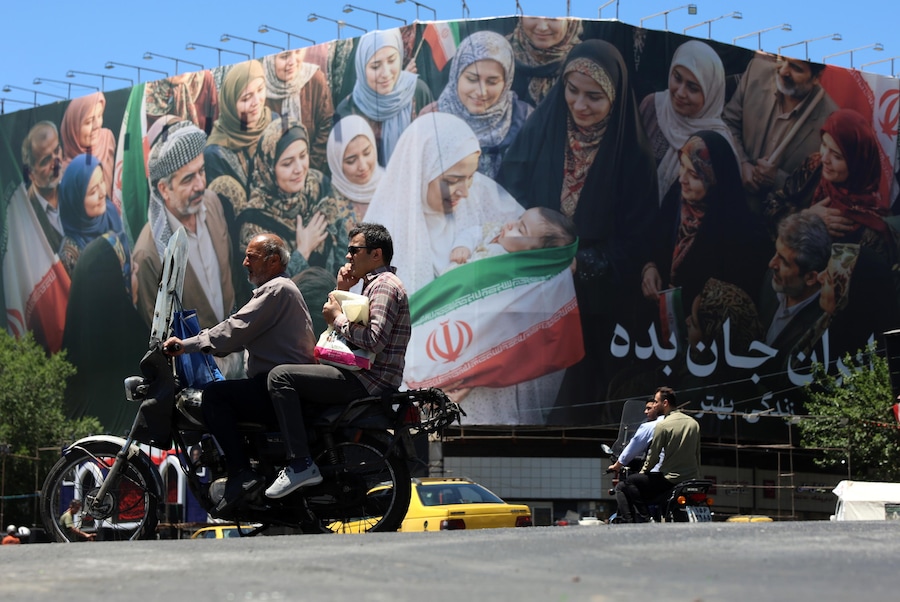 Alcuni iraniani passano in auto accanto a un enorme cartellone pubblicitario in una strada di Teheran, in Iran. (EPA)