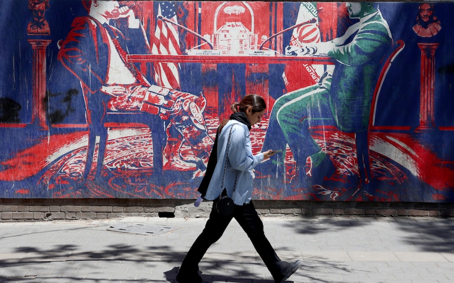 Una ragazza iraniana cammina accanto a un murale anti-statunitense che raffigura l'Iran e gli Stati Uniti seduti a un tavolo di negoziazione, nei pressi dell'ex ambasciata statunitense a Teheran, in Iran, il 26 maggio 2026. Il presidente degli Stati Uniti Donald Trump ha annunciato che un potenziale accordo di pace per porre fine al conflitto e riaprire lo Stretto di Hormuz è stato in gran parte negoziato tramite mediatori pakistani. Tuttavia, gli Stati Uniti hanno lanciato nuovi attacchi nel sud dell'Iran. EPA/ABEDIN TAHERKENAREH (EPA)