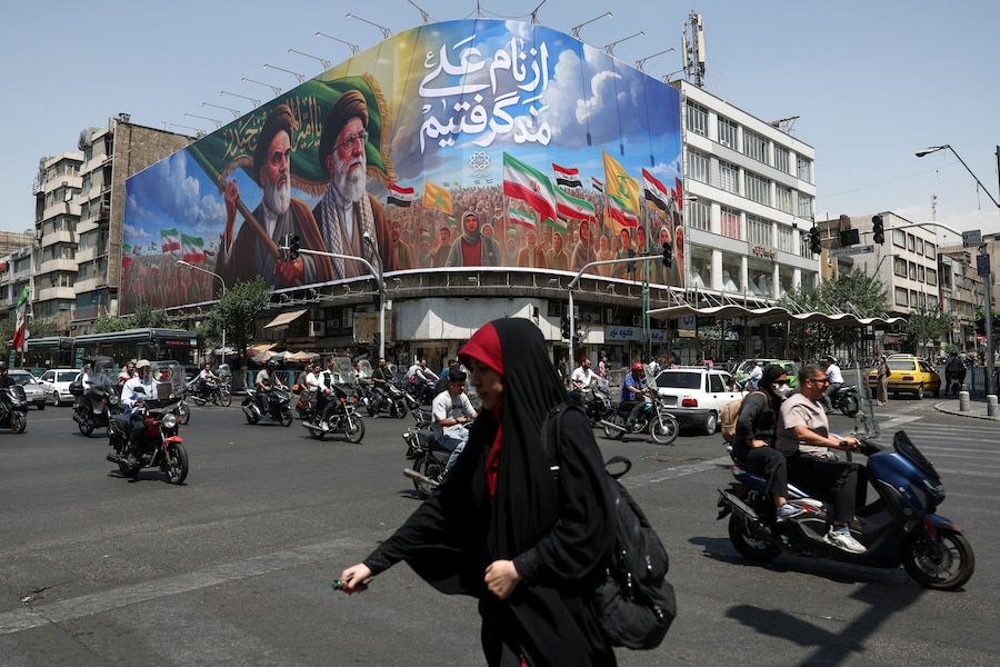 Dei passanti transitano davanti a un cartellone pubblicitario raffigurante il defunto leader della Rivoluzione Islamica, l’Ayatollah Ruhollah Khomeini, e il defunto Guida Suprema dell’Iran, l’Ayatollah Ali Khamenei, in una strada di Teheran, in Iran. (via REUTERS)
