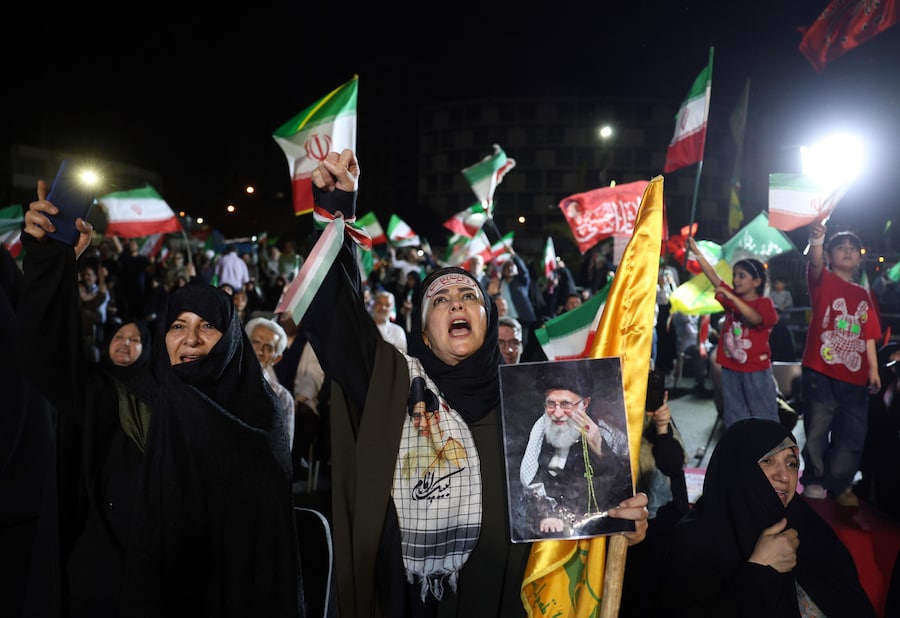 Persone sventolano bandiere iraniane e di Hezbollah durante una manifestazione in seguito all’attacco iraniano contro Israele, in piazza Valiasr a Teheran, Iran (EPA)
