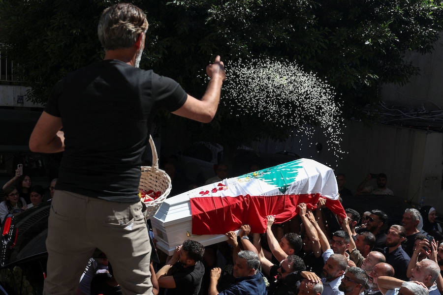 Un uomo lancia petali di fiori mentre i portatori di bara trasportano la bara durante il funerale del generale di brigata Wissam Sabra, ucciso in un attacco israeliano contro un veicolo militare sulla strada Khardali-Nabatieh, nel sud del Libano (REUTERS)