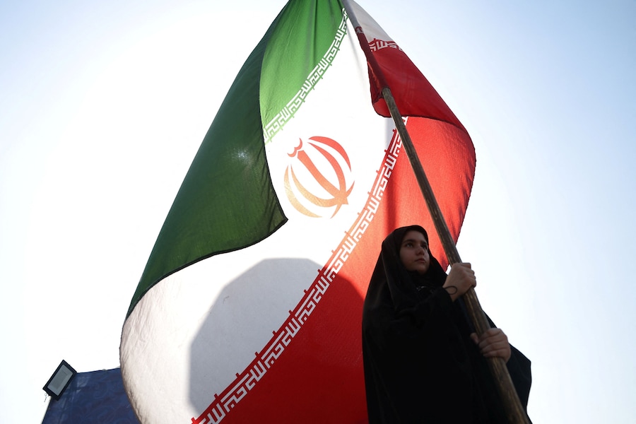 Una donna tiene in mano una bandiera iraniana in una strada di Teheran, Iran (via REUTERS)
