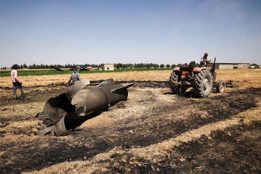 Un agricoltore trascina un missile iraniano, secondo quanto riferito dalle autorità locali, con il suo trattore nel suo campo dopo che le squadre di ingegneri militari lo avevano dichiarato sicuro, nelle campagne vicino a Damasco, in Siria (REUTERS)