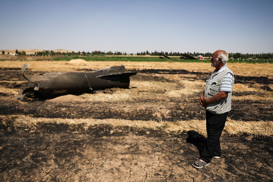 Un agricoltore si trova accanto a un missile iraniano, secondo le autorità locali, caduto nel suo campo nella campagna vicino a Damasco, in Siria (REUTERS)