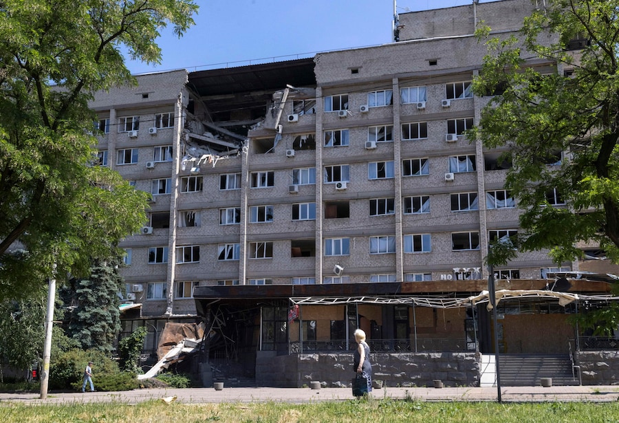 Residenti locali camminano accanto a un edificio danneggiato nel luogo di un raid aereo russo su una zona residenziale nella città di prima linea di Kramatorsk, nella regione di Donetsk, Ucraina orientale (EPA)