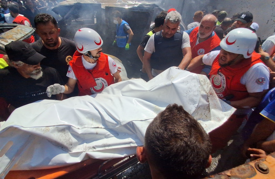 I paramedici trasportano un cadavere a lato dell’auto colpita da un raid aereo israeliano nella città portuale meridionale di Sidone, in Libano (APN)