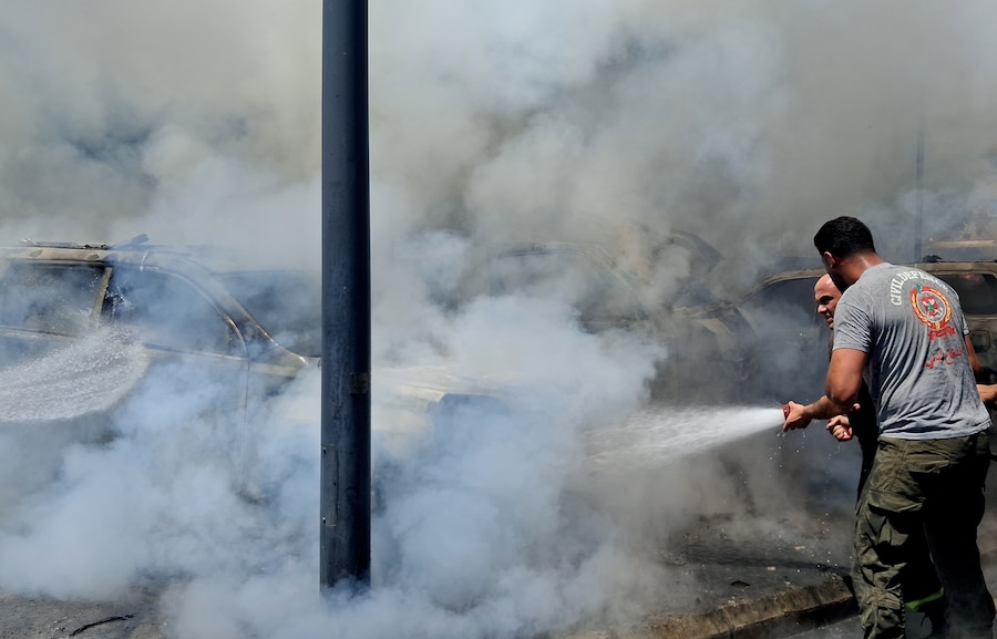I vigili del fuoco spengono le auto bruciate che sono state colpite da un raid aereo israeliano nella città portuale meridionale di Sidone, in Libano (APN)