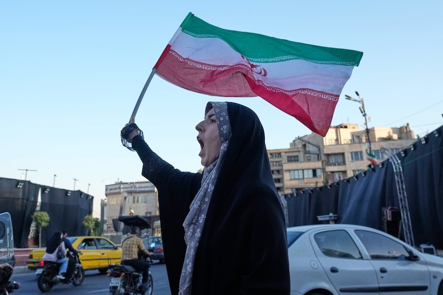 Una donna sventola una bandiera iraniana mentre scandisce slogan contro i colloqui tra Iran e Stati Uniti nella piazza della Rivoluzione islamica a Teheran, Iran (APN)