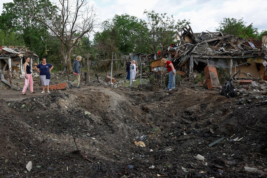 La gente si raduna accanto a un cratere formatosi in una zona residenziale durante i bombardamenti russi con missili e droni, a Kiev. (REUTERS/Valentyn Ogirenko)