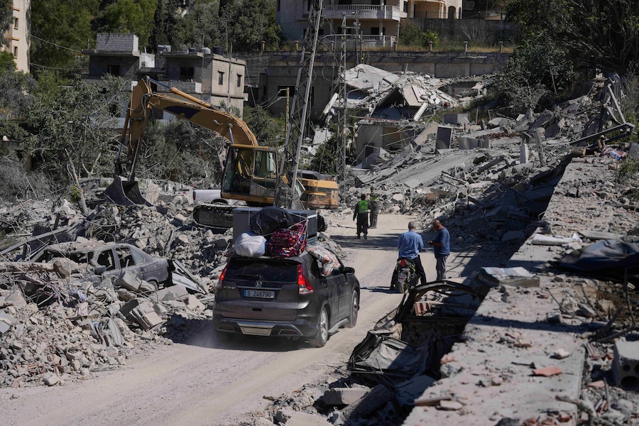 Persone che tornano al loro villaggio dopo l’annuncio di un primo accordo di cessate il fuoco tra Stati Uniti e Iran percorrono una strada danneggiata da precedenti raid aerei israeliani nel villaggio meridionale di Kherbet Selem, in Libano (APN)