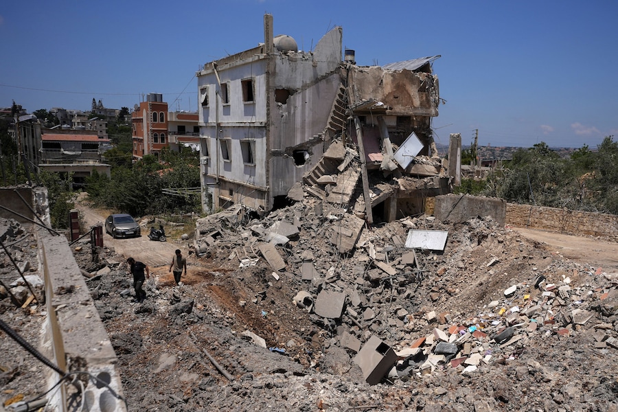 Alcune persone ispezionano il sito di un precedente attacco israeliano a Kfar Sir, nel distretto di Nabatieh, in Libano (REUTERS)