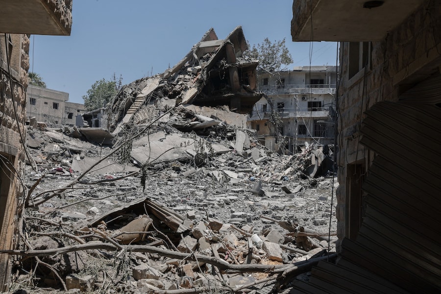 Un piccione è appollaiato su un ramo vicino ad alcuni edifici residenziali danneggiati dai raid israeliani a Nabatieh, in Libano (REUTERS)