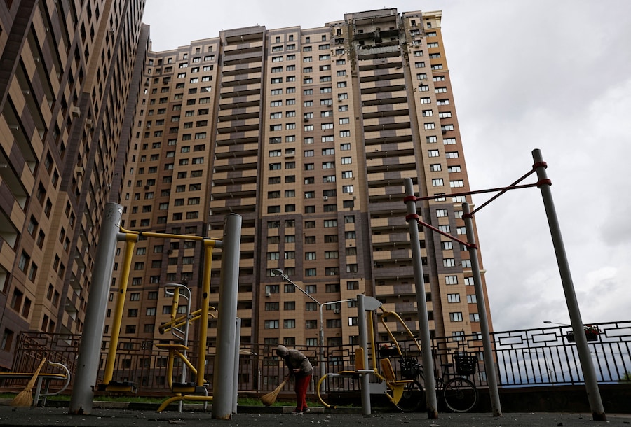 Una persona spazza via i detriti davanti a un condominio danneggiato in seguito a un attacco di un drone ucraino a Zhukovsky, nella regione di Mosca, Russia (REUTERS)