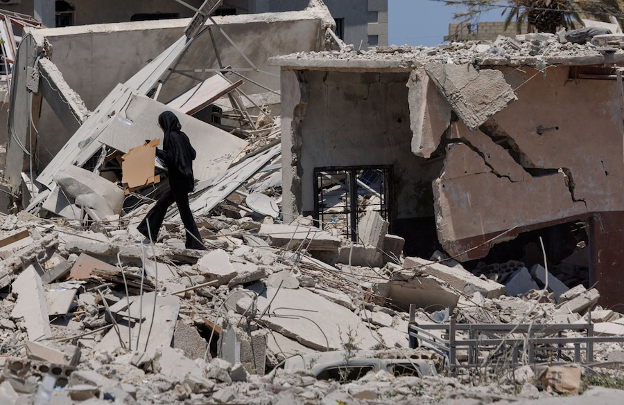 Una donna tiene in mano i propri effetti personali mentre cammina tra le macerie di un quartiere completamente distrutto da un attacco aereo israeliano, a seguito dell’accordo tra Stati Uniti e Iran, a Qlailieh, nel distretto di Tiro, in Libano. (REUTERS/Zohra Bensemra)
