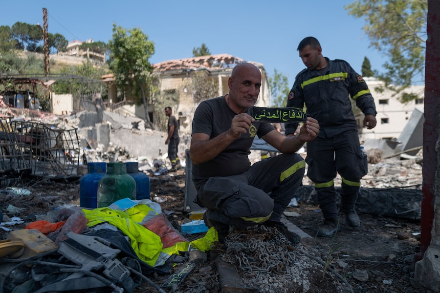 Un membro della Protezione Civile libanese, l’ente governativo che costituisce la principale forza del Paese per la lotta agli incendi, il primo soccorso e il salvataggio, tiene in mano un distintivo dell’uniforme su cui si legge “protezione civile”, recuperato dalle macerie durante un’ispezione della sede centrale a Nabatieh, in Libano, a seguito dell’accordo tra Stati Uniti e Iran. Il quartier generale era stato distrutto da un attacco aereo israeliano nel mese di maggio. (REUTERS/Zohra Bensemra)