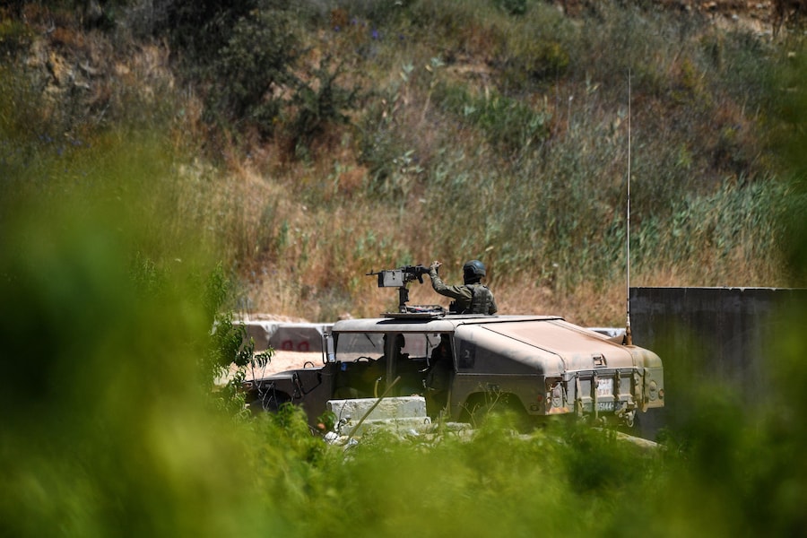 Veicoli militari israeliani percorrono una strada israeliana lungo il confine tra Israele e il Libano, nel nord di Israele. (REUTERS/Gil Eliyahu)