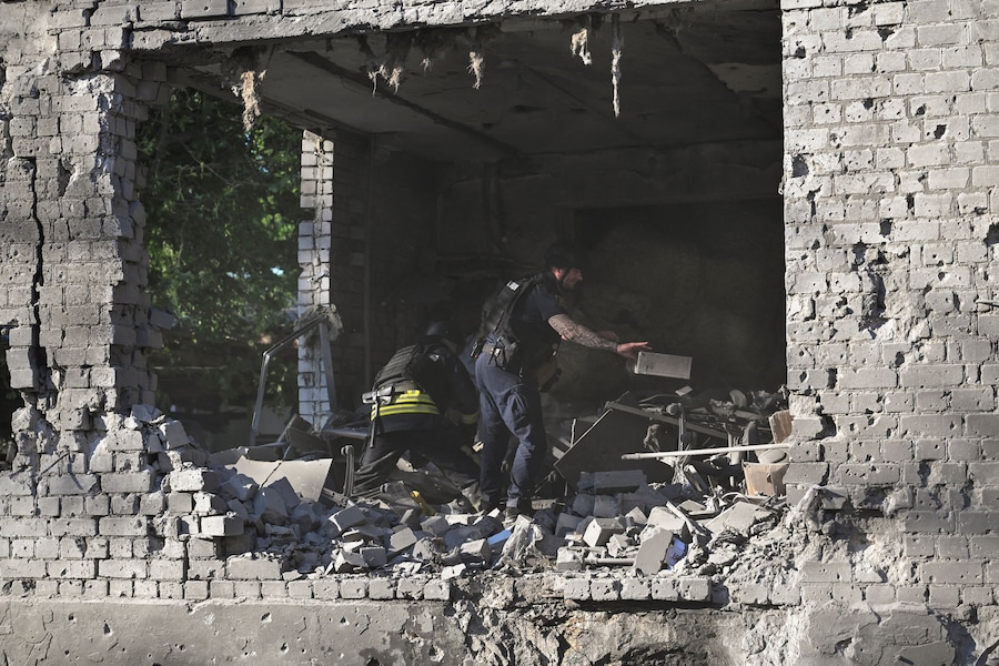 Un agente di polizia e un soccorritore rimuovono le macerie sul luogo in cui sorgeva un edificio amministrativo colpito da un attacco aereo russo, a Zaporizhzhia. (REUTERS/Stringer)