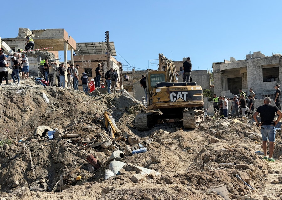 Civili e personale della Croce Rossa libanese si trovano tra le macerie di un edificio danneggiato, mentre un bulldozer contribuisce alle operazioni di ricerca delle vittime a seguito di un attacco israeliano al villaggio di Qennarit, nel Libano meridionale. (REUTERS/Stringer)