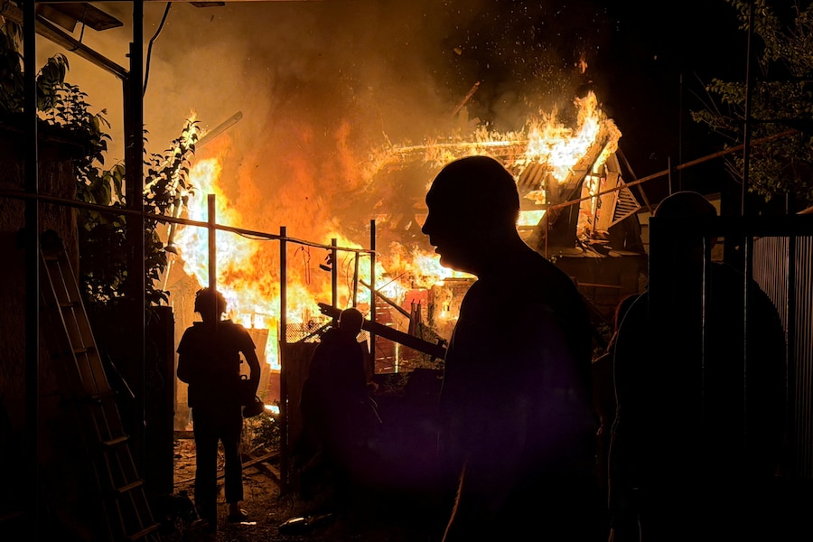 Alcuni residenti osservano una casa privata in fiamme dopo un attacco notturno sferrato da un drone russo, nel contesto dell'offensiva russa contro l'Ucraina, a Zaporizhzhia. (REUTERS/Serhii Chalyi)