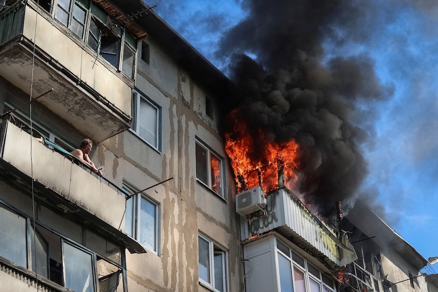 Un residente osserva dal proprio balcone mentre un altro appartamento va in fiamme dopo essere stato colpito da un drone russo, nel corso dell'attacco della Russia all'Ucraina, nella città di Druzhkivka, in prima linea nella regione di Donetsk. (REUTERS/Anatolii Stepanov)