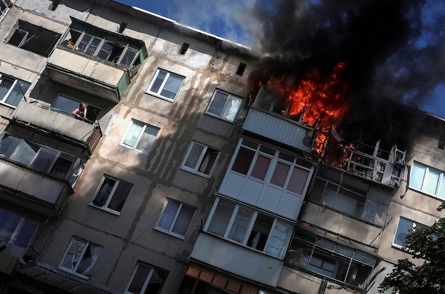 Un residente osserva dal proprio balcone mentre un altro appartamento va a fuoco dopo essere stato colpito da un drone russo, nel corso dell’attacco della Russia all’Ucraina, nella città di Druzhkivka, in prima linea nella regione di Donetsk. (REUTERS/Anatolii Stepanov)