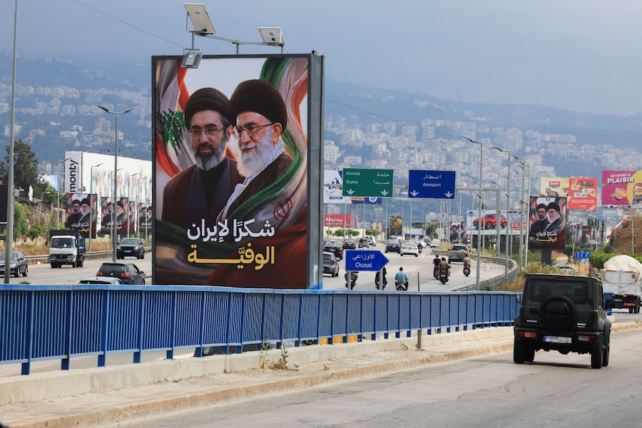 Auto e moto sfrecciano davanti ai cartelloni che ritraggono il nuovo leader supremo dell’Iran, l’ayatollah Mojtaba Khamenei, e il suo defunto padre Ali Khamenei, con lo slogan «Grazie all’Iran leale», lungo l’autostrada che conduce all’aeroporto internazionale Rafic Hariri di Beirut, in Libano, il 22 giugno 2026. (REUTERS)
