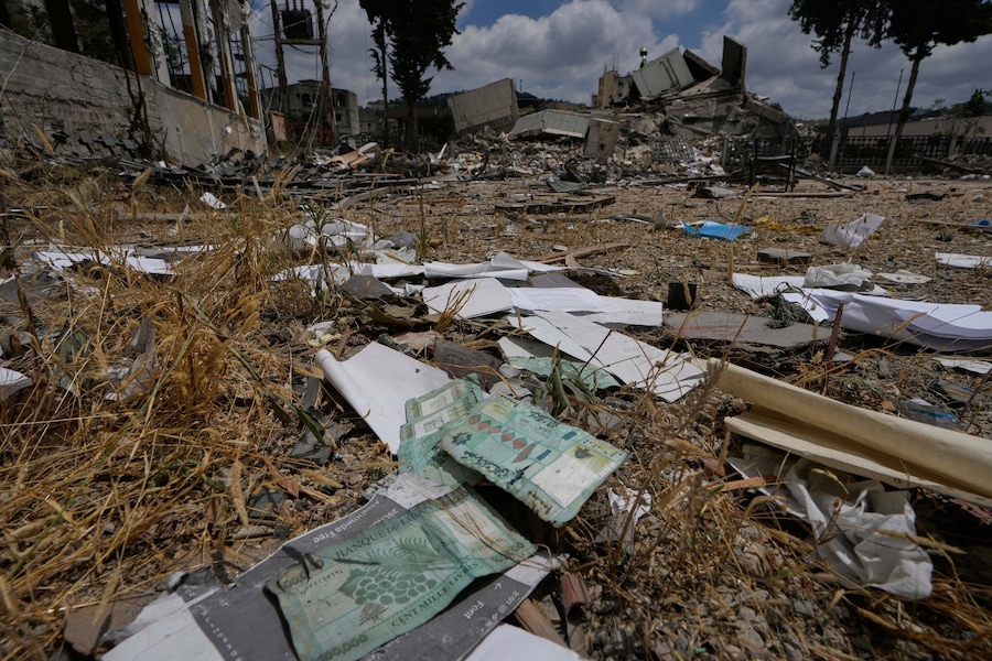 Denaro libanese e documenti ufficiali giacciono a terra davanti a una filiale distrutta della Banca Centrale Libanese nella città di Nabatiyeh, nel sud del Libano (APN)