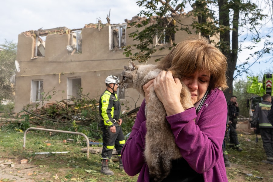 Una donna tiene in braccio il suo gatto dopo che è stato ritrovato durante le operazioni di ricerca e soccorso nell’edificio residenziale danneggiato dall’attacco missilistico russo a Kharkiv, in Ucraina (APS)