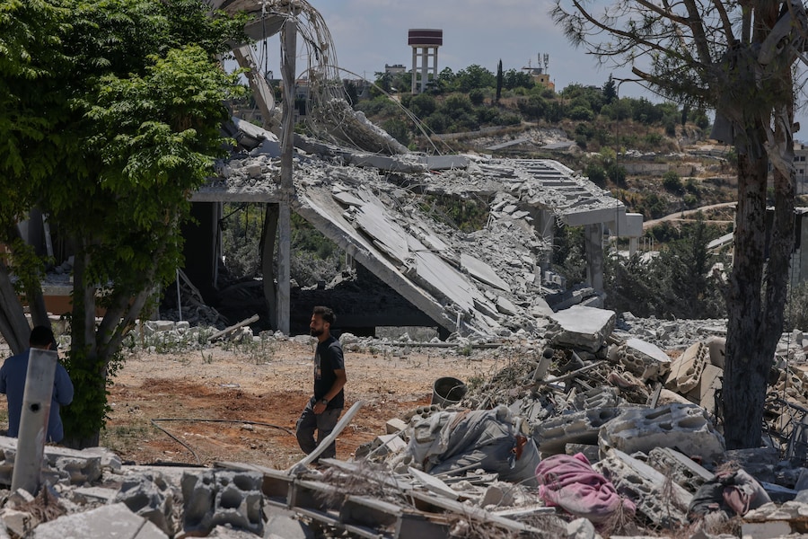 Hadi Hussein, un dipendente comunale che afferma di non aver lasciato il villaggio durante la guerra – e che si occupa di sgomberare le strade dopo gli attacchi israeliani e di fornire acqua ed elettricità ai residenti rimasti – cammina accanto ad alcune case distrutte da un attacco aereo israeliano ad Al Halloussiyah, nel distretto di Tiro (Libano meridionale) (REUTERS)