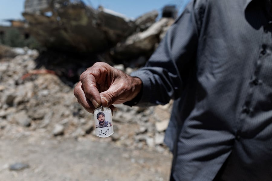 Un uomo libanese sfollato di 76 anni mostra una foto del figlio – che, a suo dire, era un combattente di Hezbollah rimasto ucciso in un attacco israeliano – mentre si trova davanti alla propria casa distrutta da un raid aereo israeliano, dopo aver fatto ritorno a Maaroub, municipalità del distretto di Tiro nel Libano meridionale (REUTERS)