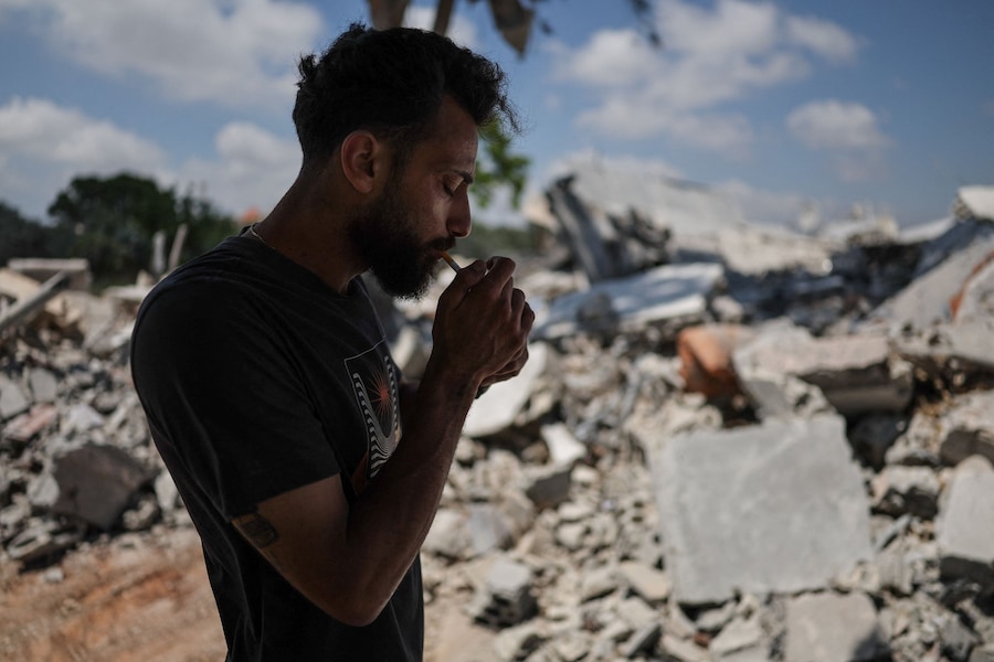 Hadi Hussein, un dipendente comunale che ha affermato di non aver lasciato il villaggio durante la guerra – e che si occupa di sgomberare le strade dopo gli attacchi israeliani e di fornire acqua ed elettricità ai residenti rimasti – accende una sigaretta davanti alla sua casa distrutta in un attacco aereo israeliano, ad Al Halloussiyah, nel distretto di Tiro (Libano meridionale) (REUTERS)