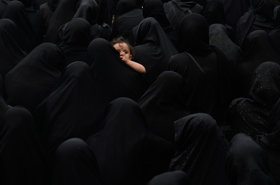 Una donna tiene in braccio un bambino durante una cerimonia di lutto a Teheran, in Iran (APN)