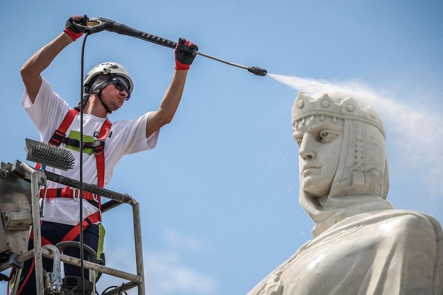 Un operaio pulisce il monumento alla principessa Olga accanto a una mostra di mezzi militari russi distrutti in piazza Mykhailivska a Kiev, in Ucraina. (REUTERS)