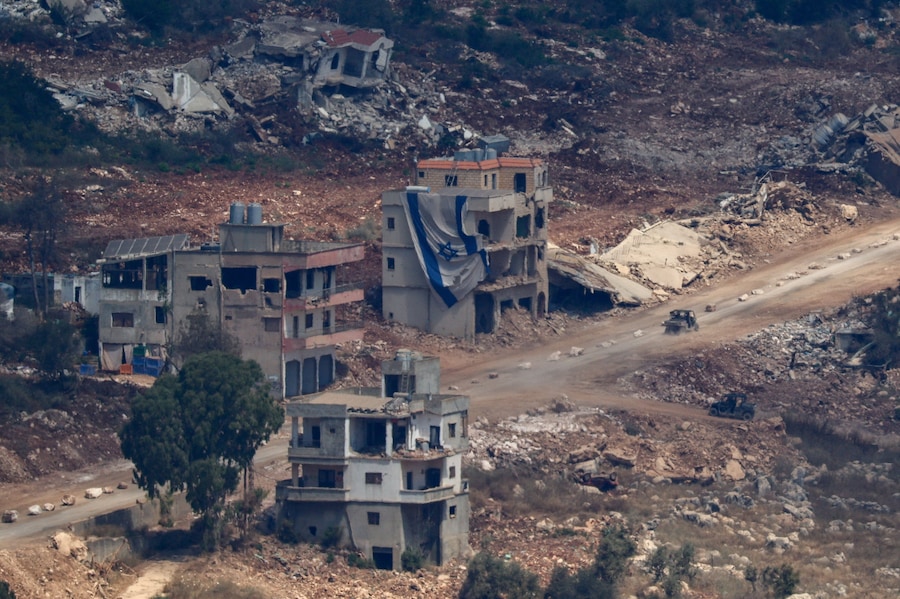 Un veicolo militare israeliano transita nei pressi di un edificio danneggiato su cui sventola una grande bandiera israeliana in Libano, dopo che Israele e Libano hanno firmato un accordo quadro a seguito dei colloqui mediati dagli Stati Uniti. (REUTERS)