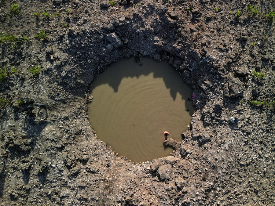 Una ripresa dal drone mostra un uomo israeliano che nuota in un cratere pieno d’acqua, formatosi a seguito dell’impatto di un missile iraniano che il mese scorso ha colpito un campo agricolo e che, secondo i residenti locali, ha portato alla luce una sorgente sotterranea naturale che ha riempito il cratere, nei pressi di Bat Shlomo, nel nord di Israele, il 27 giugno 2026. (REUTERS)
