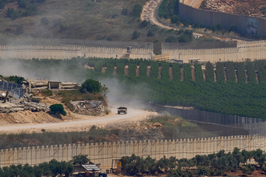 Un veicolo militare israeliano passa davanti a edifici distrutti nel Libano meridionale, visto dal nord di Israele. (APN)