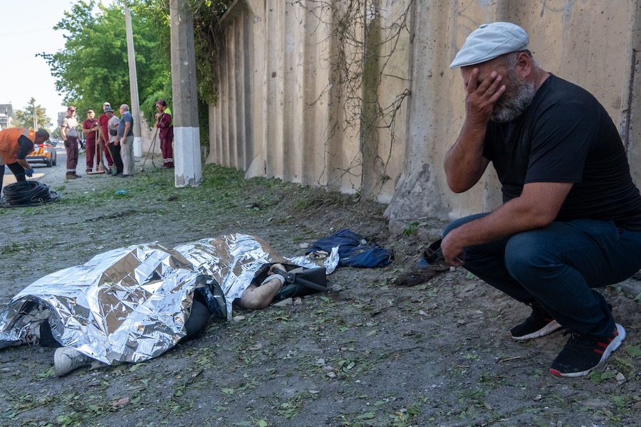 Un uomo piange accanto al corpo di un suo parente rimasto ucciso durante un attacco aereo a Kharkiv. (APN)