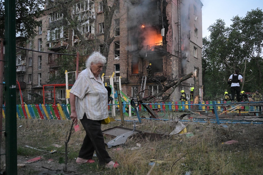 Una donna passa davanti a un condominio in fiamme dopo un attacco missilistico russo a Kiev. (APN)