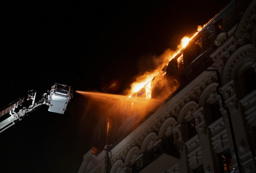 Vigili del fuoco ucraini operano sul luogo colpito da un drone russo – un edificio adibito a hotel – nel centro di Kiev (EPA)