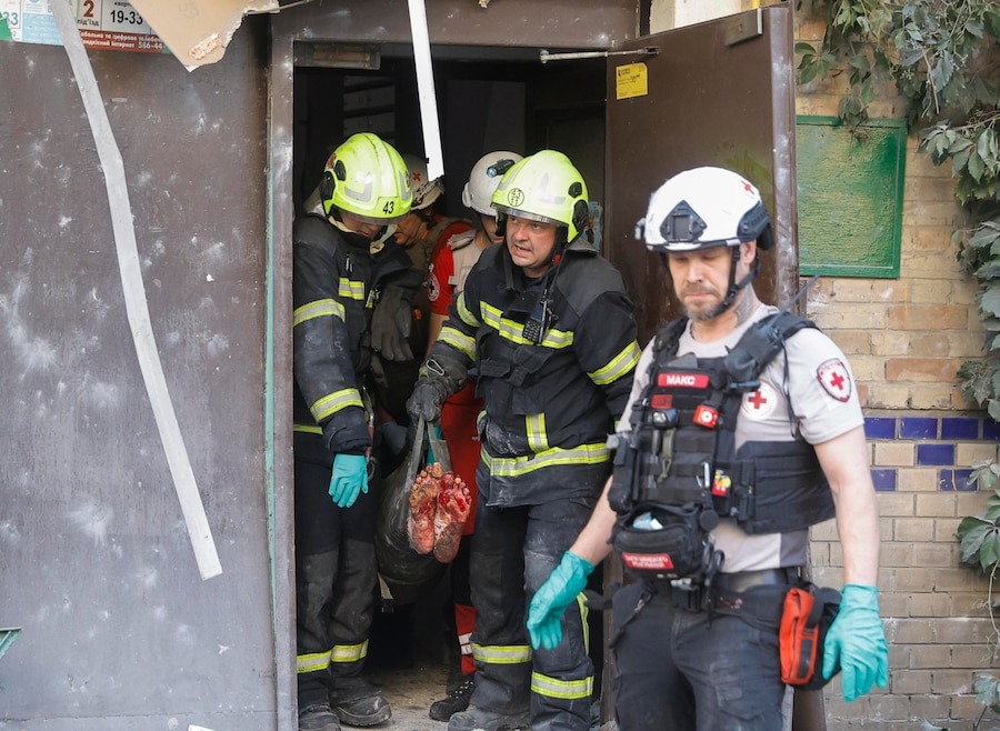 Soccorritori e personale medico ucraini trasportano un uomo ferito sul luogo colpito da un missile russo – un edificio residenziale di nove piani – a Kiev (EPA)