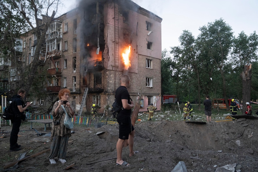 Alcuni residenti si radunano sul luogo colpito da un missile russo in una zona residenziale di Kiev (EPA)