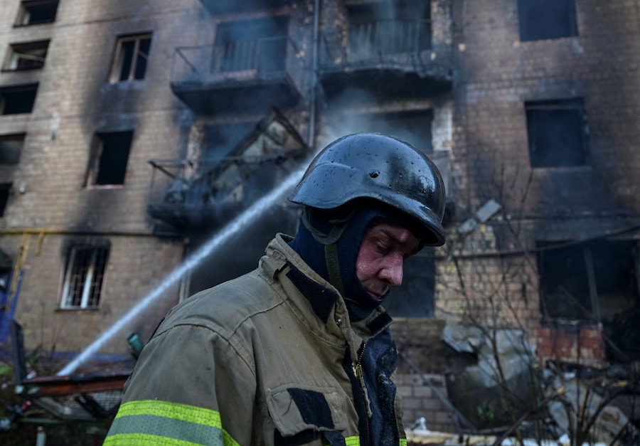 Un vigile del fuoco cammina vicino a un condominio danneggiato durante un attacco russo con missili e droni a Kiev (REUTERS)