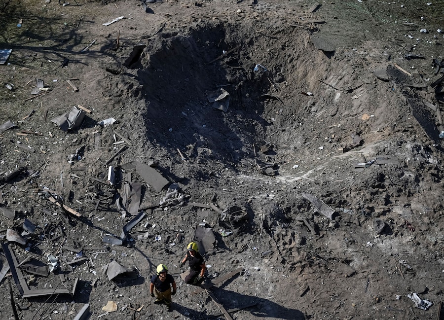 Alcuni soccorritori si trovano accanto a un cratere formatosi in un sito colpito durante gli attacchi notturni russi con missili e droni a Kiev (REUTERS)