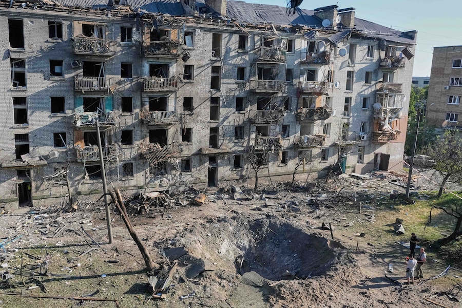 Alcune persone osservano il luogo colpito da un missile russo che ha centrato un edificio residenziale a Kiev (APN)
