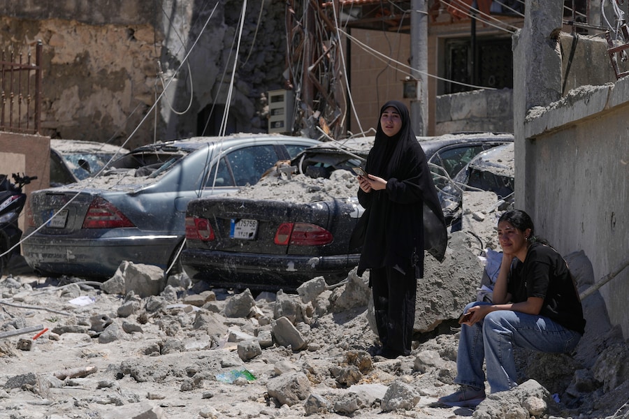 I parenti delle vittime disperse piangono mentre si radunano sul luogo degli edifici distrutti, colpiti da un attacco aereo israeliano nel villaggio di Qannarit, nel Libano meridionale. (AP Photo/Mohammed Zaatari) (APN)